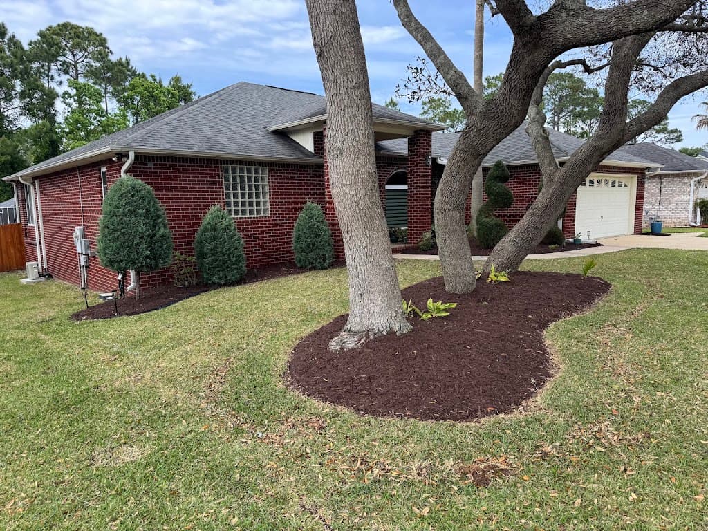 Mulched tree rings and a manicured lawn at a red brick home